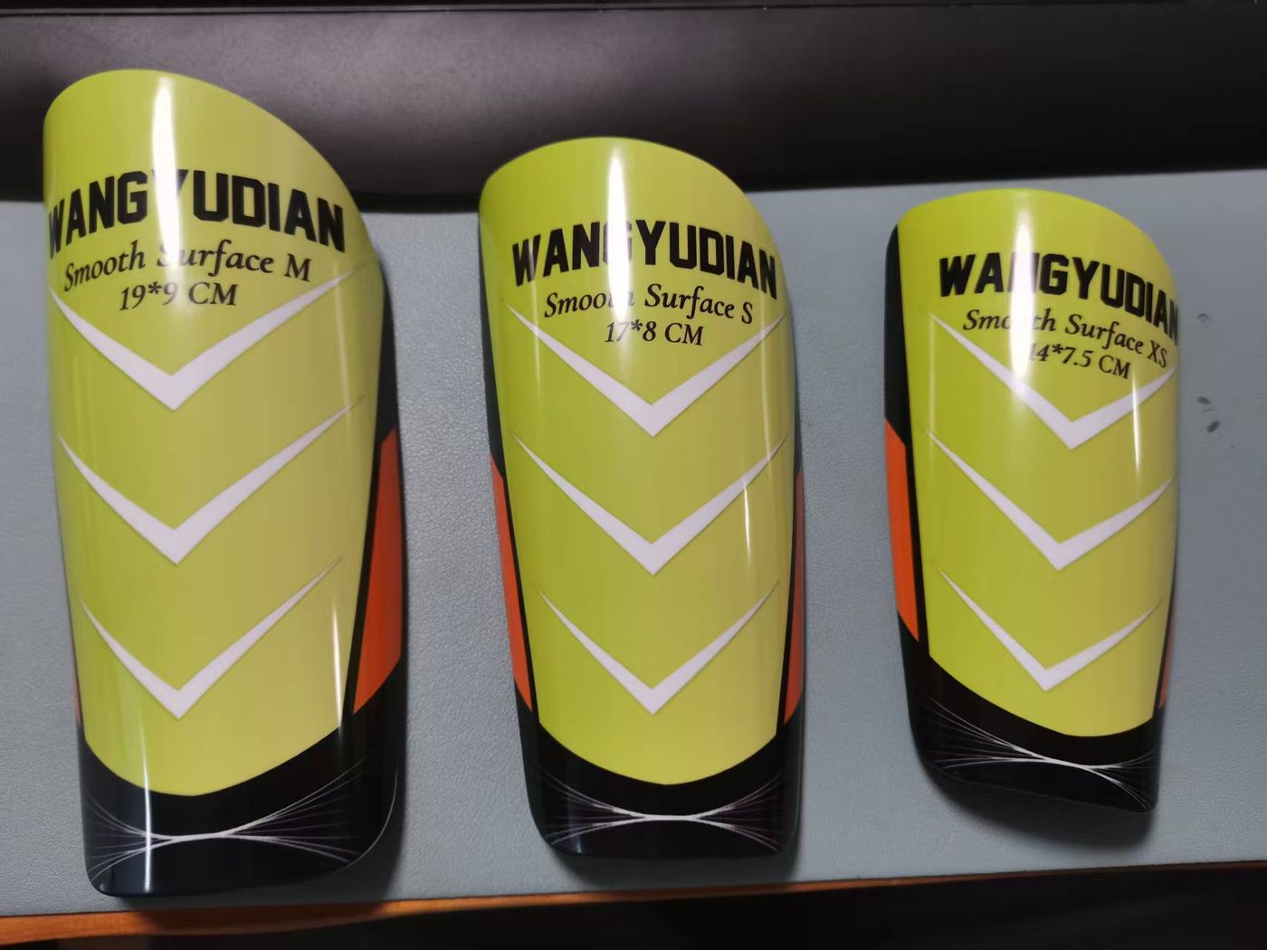 Smooth full-size shin guards labelled M 19 × 9 cm, S 17 × 8 cm and XS 14 × 7.5 cm