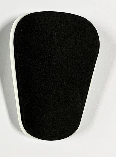 Foam-lined back of a mini shin guard with a white shell edge