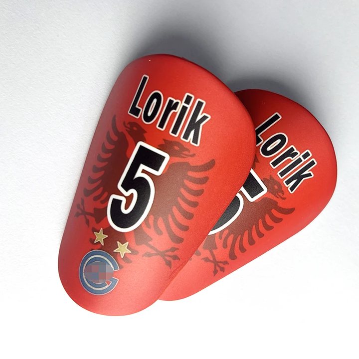 Pair of red mini shin guards printed 'Lorik 5'