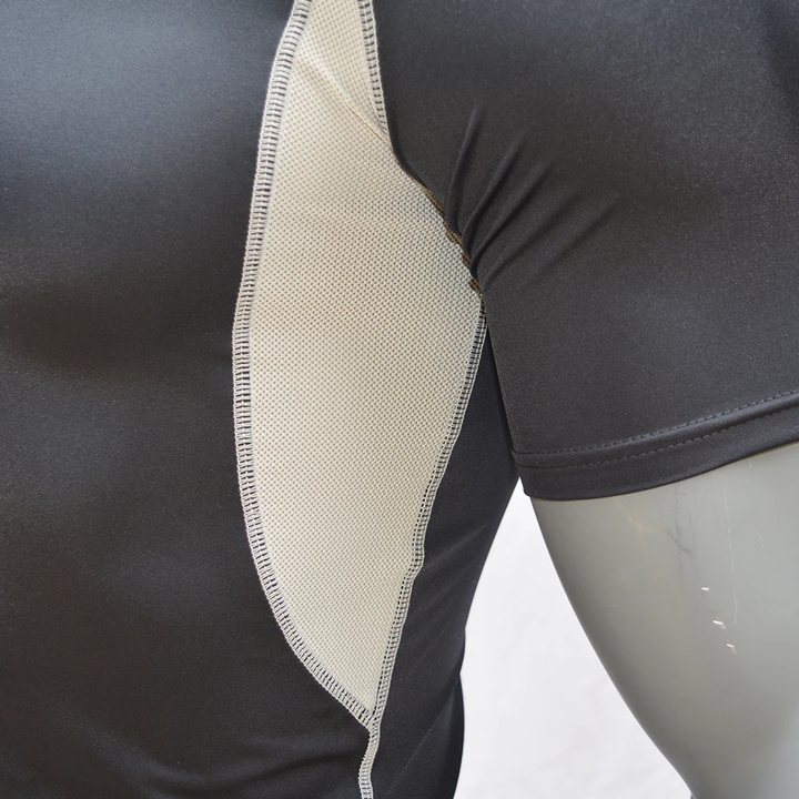 Beige mesh side panel of a black short-sleeve rash guard, close-up