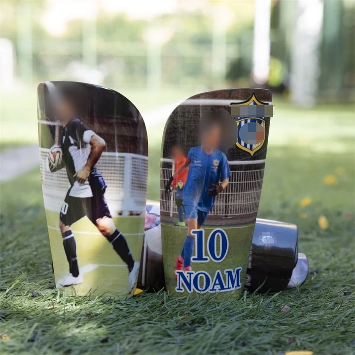 Two full-size shin guards printed with player photos, a name and the number 10, standing on turf
