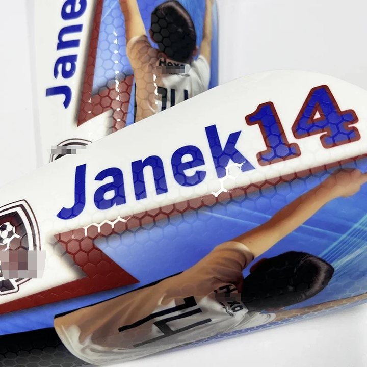 Close-up of two honeycomb-textured shin guards printed 'Janek 14' with a player photo