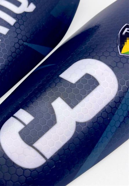 Close-up of honeycomb-textured shin guards printed with a name and the number 3